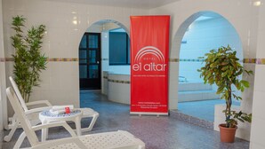A hotel lobby with a reception desk, a red banner, a pool area, and lounge chairs. - Hotel El Altar (Riobamba)