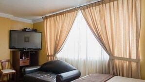 A hotel room with a bed, a chair, a television, and curtains. - Hotel El Altar (Riobamba)