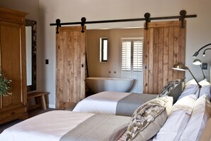 A bedroom with two beds, a wooden wardrobe, a large mirror, a sink, and a hanging light fixture. - d'Olyfboom Guest Rooms (Paarl)