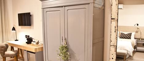 A bedroom with a large wardrobe, a desk with a lamp, and a bed with a nightstand.