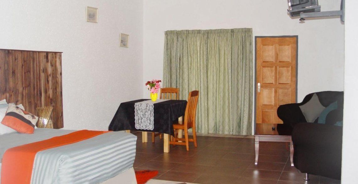 Una habitación con una cama, una mesa con una silla, un sofá y una puerta.