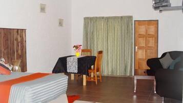 Una habitación con una cama, una mesa con una silla, un sofá y una puerta.
