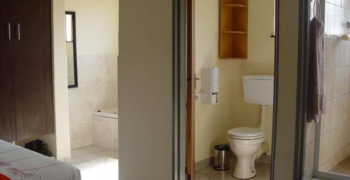Un baño con inodoro, lavamanos y espejo.