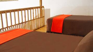 A room with two beds, each covered with brown sheets and orange blankets.