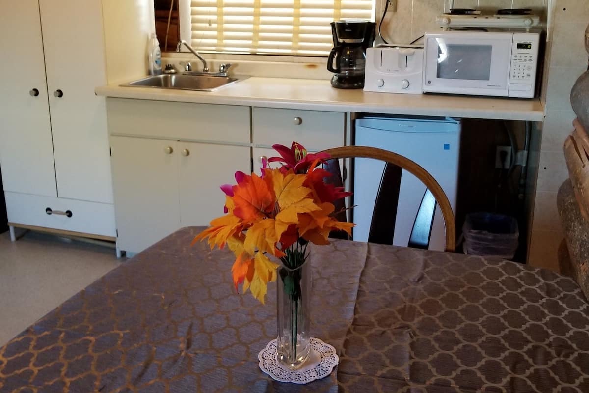 A compact kitchen with a microwave, coffee maker, and a television on a cabinet.