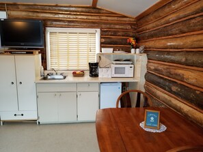 A compact kitchen with a sink, microwave, toaster, and a television on a cabinet. - Christina Lake Lodge (Conklin)