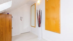 Un pasillo con paredes blancas, una puerta de madera y un espejo.