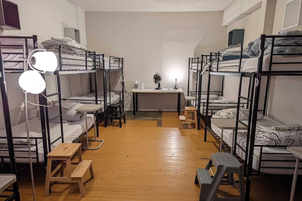 Asuntolan huone, jossa on kerrossängyt, työpöytä ja lattiavalaisin.