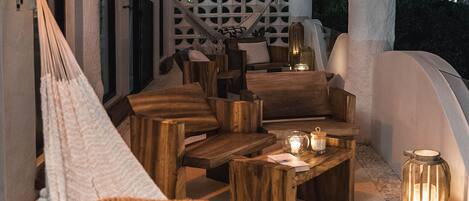 A hammock, wooden furniture, and candles in an outdoor seating area.