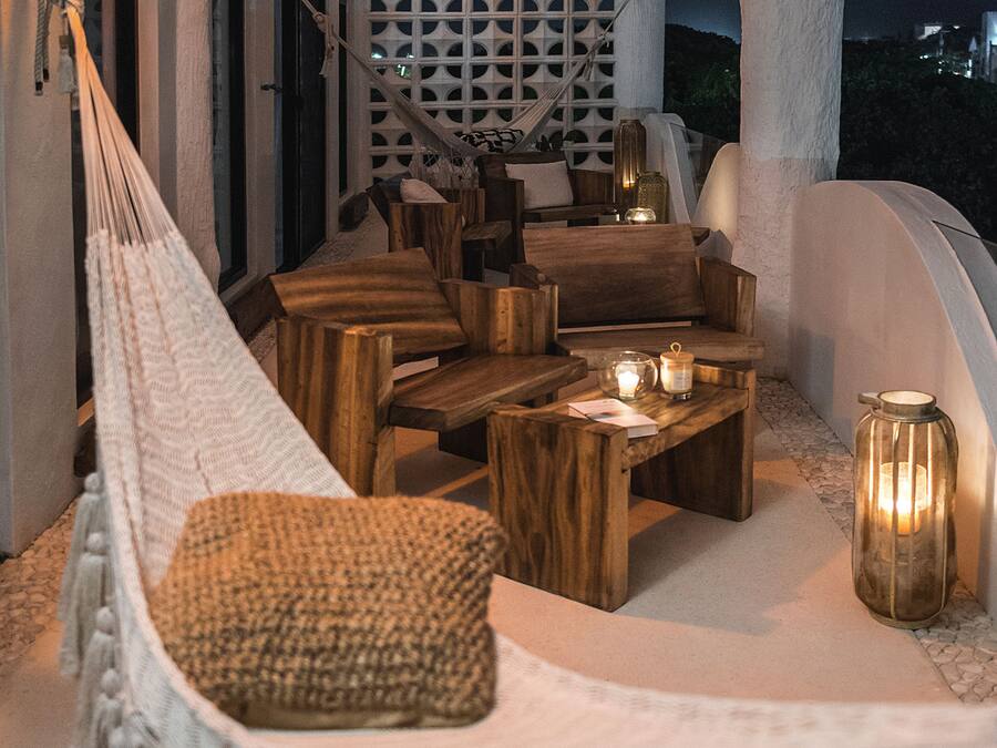 A hammock, wooden furniture, and candles in an outdoor seating area.