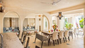 Amplia sala de estar con mesa de comedor, asientos cómodos y ventanas grandes que ofrecen vistas al exterior.