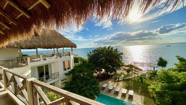 Un resort con piscina, sillas de descanso y vista al mar.