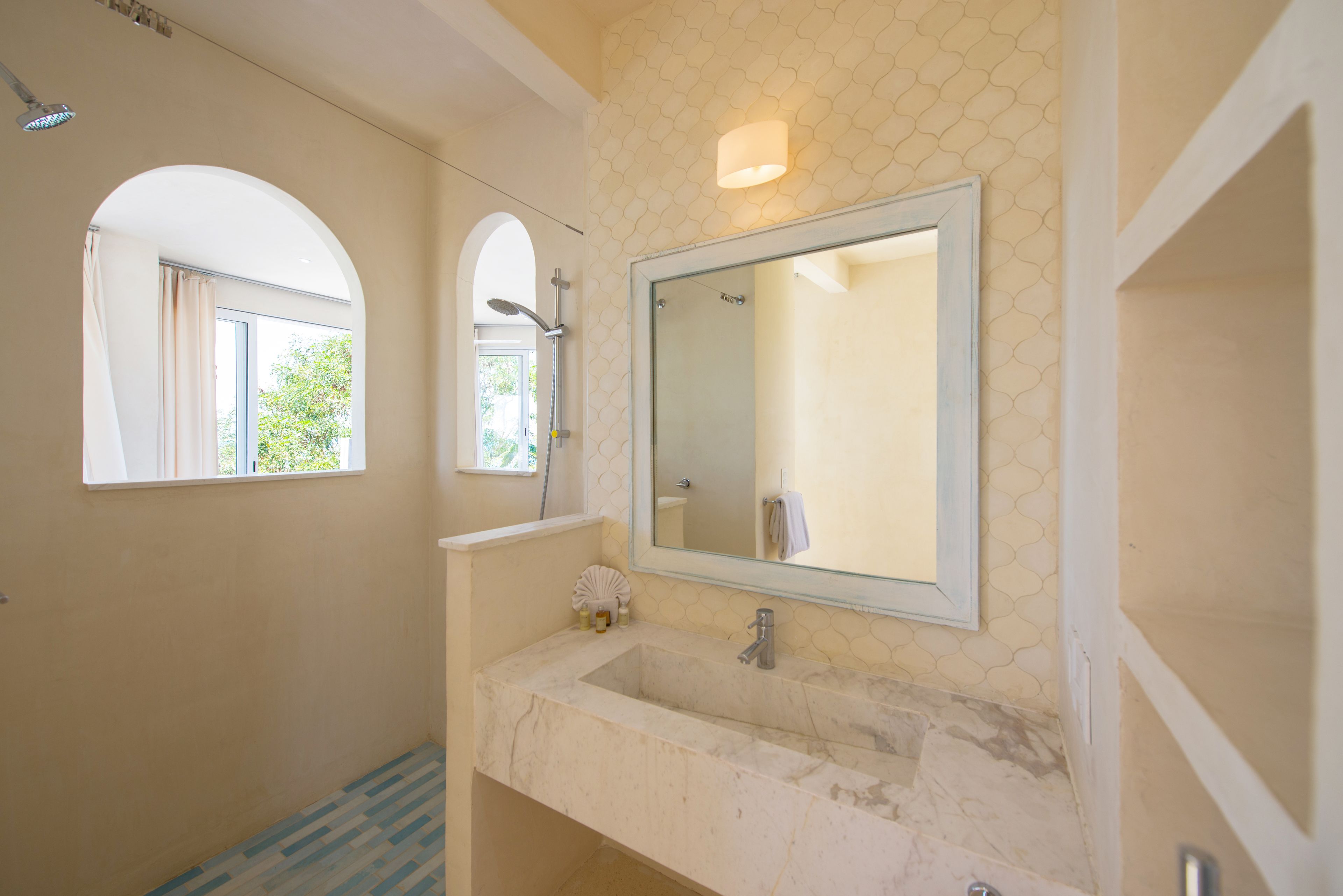 Een badkamer met een grote spiegel, een wastafel en een douche.