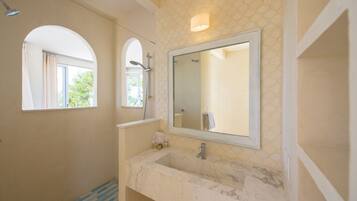 A bathroom with a large mirror, a sink, and a shower.