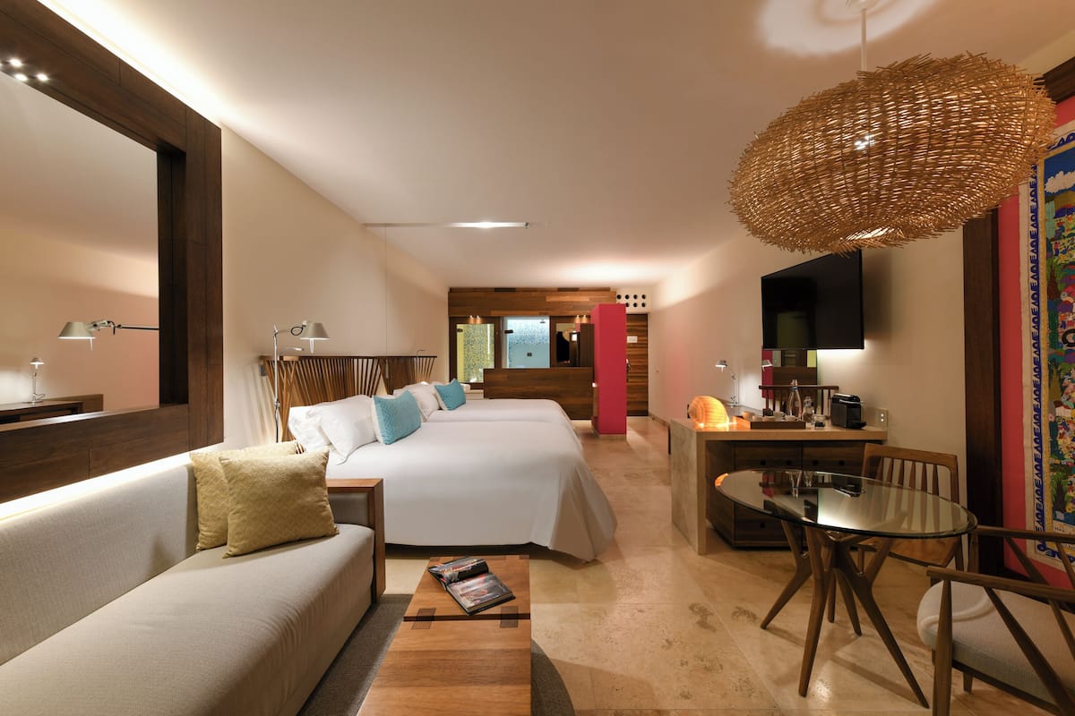 A hotel room with a sofa, a bed, a dining table, and a TV.