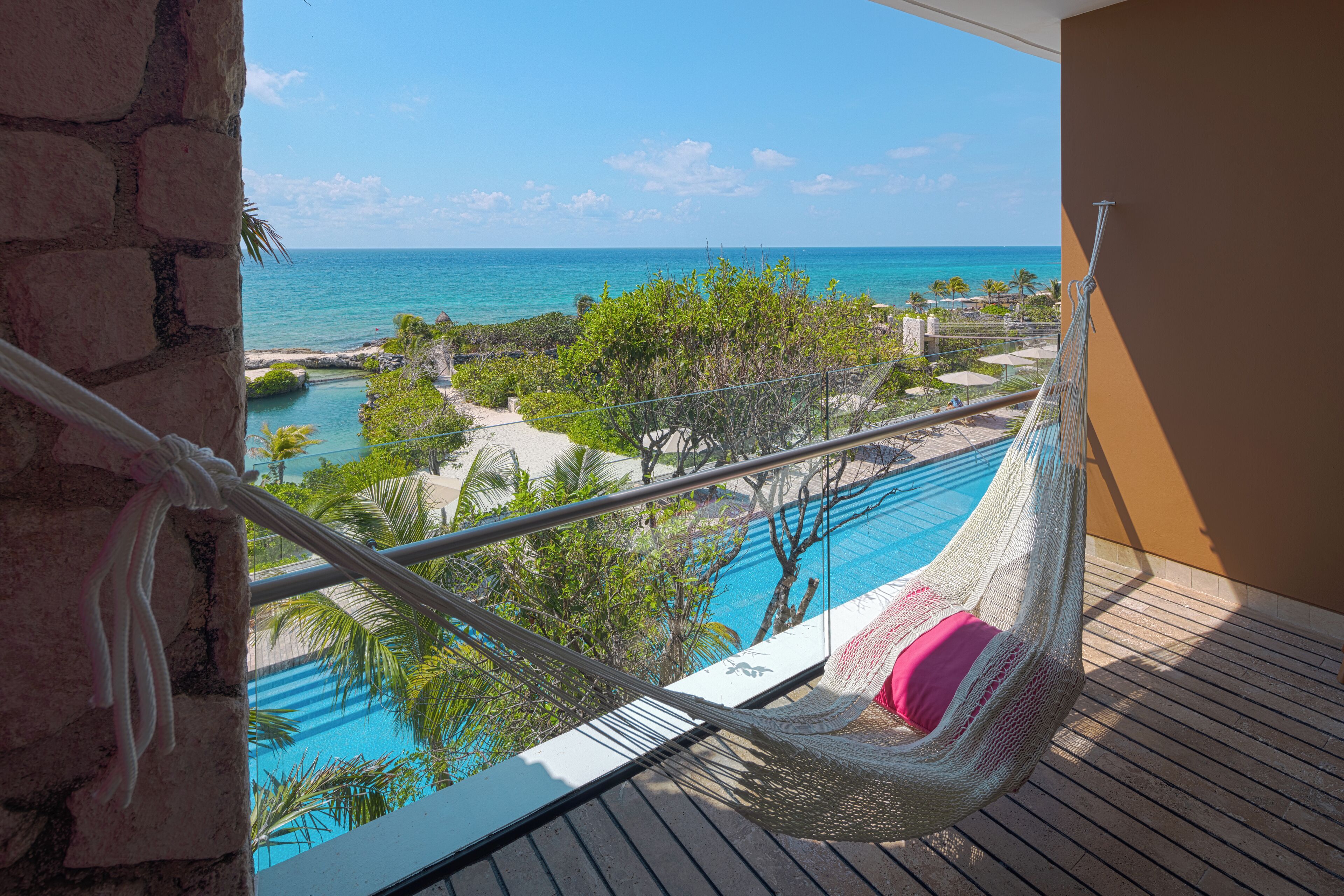Una hamaca en un balcón con vista a una piscina y una playa.