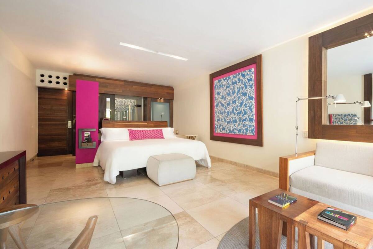 A modern bedroom with a bed, bedside tables, a sofa, and a large mirror.