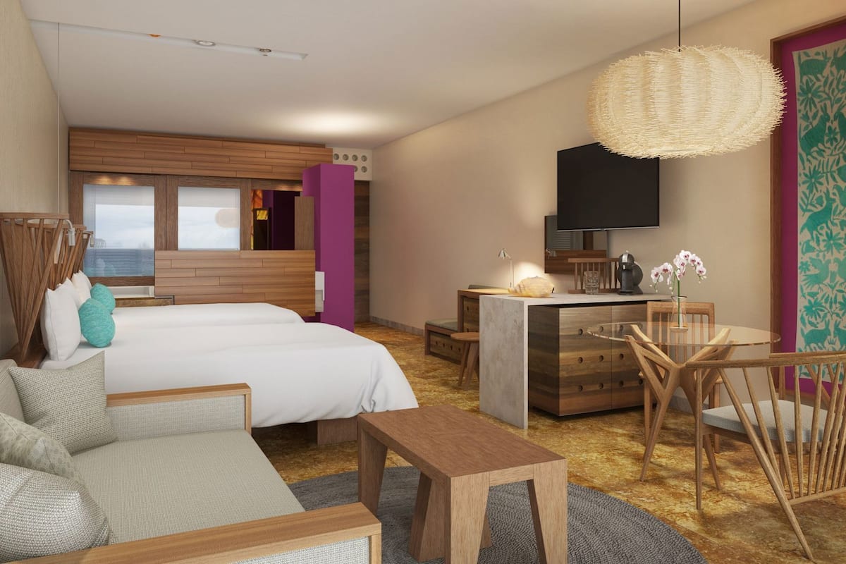 A hotel room with a bed, sofa, desk, chairs, a TV, and a large window.
