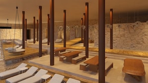 A spa area with lounge chairs, wooden tables, and stone walls. - Hotel Xcaret Tierra - Family Premier - All inclusive (Playa del Carmen)
