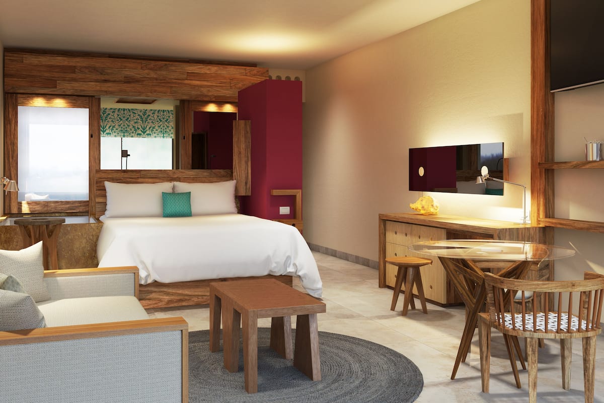 Une chambre d’hôtel moderne, dotée d’un grand lit, d’un bureau, d’une chaise et d’un canapé.