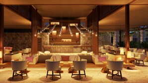 A spacious lounge area with multiple seating arrangements, a central bar, and a stone wall backdrop. - Hotel Xcaret Tierra - Family Premier - All inclusive (Playa del Carmen)