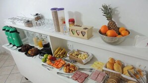Un bufé con diversas opciones de comida, incluyendo frutas, pan y salsas.
