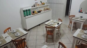 Un espace repas avec des tables disposées pour accueillir quatre personnes, des chaises et un comptoir blanc sur lequel sont placés divers objets.