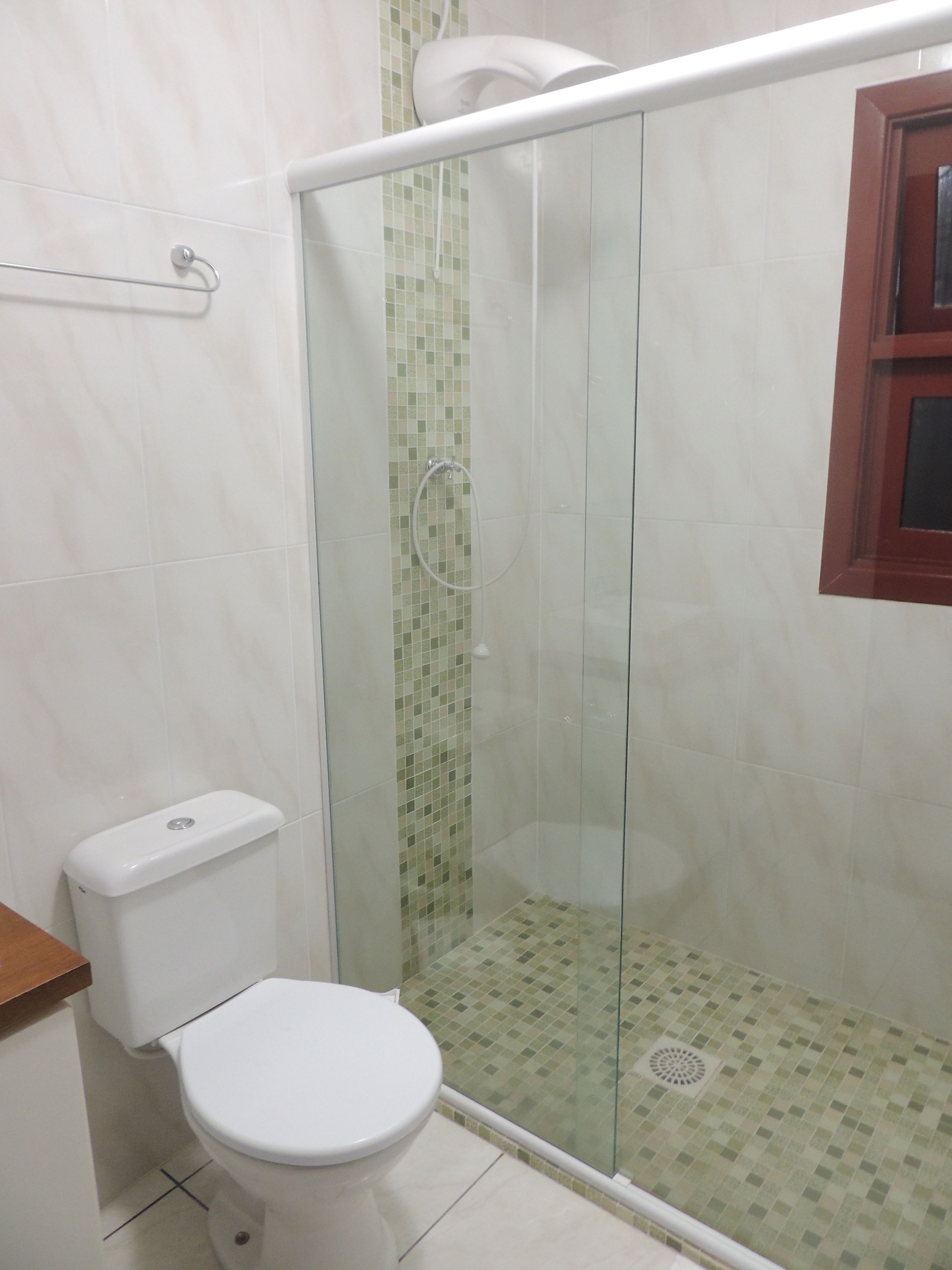 A bathroom with a toilet, a glass-enclosed shower, and a tiled floor.