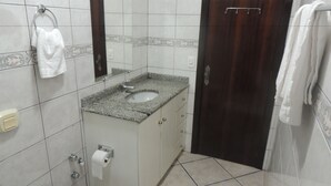 Un baño con lavamanos, espejo, toallero, inodoro y puerta.
