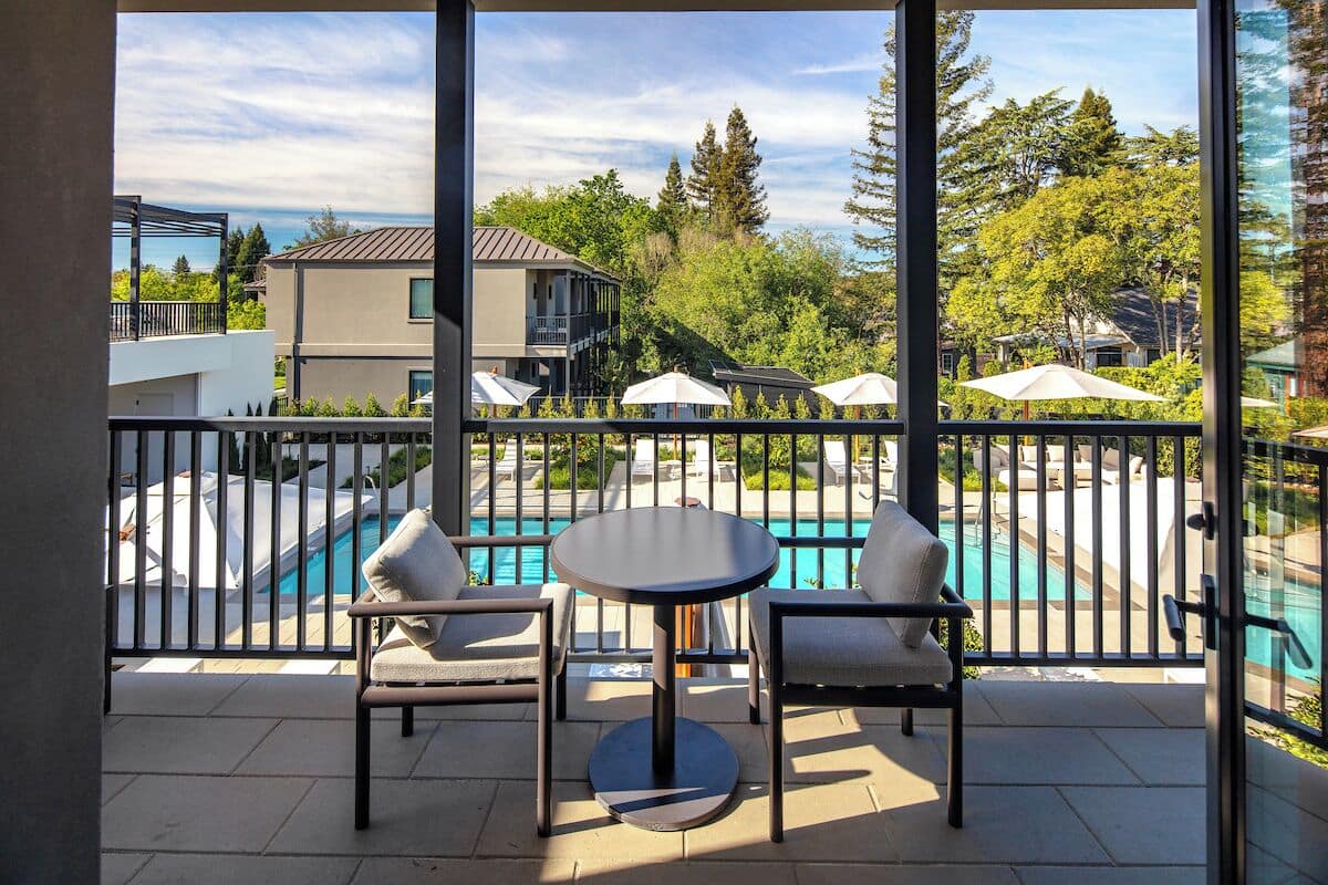 Ein Balkon mit Blick auf einen Pool, Sitzgelegenheiten im Freien und einer Brüstung.