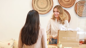 A person holding a shopping bag with "BON TON STUDIO" text, standing in a room with woven wall decorations. - Duchamp Healdsburg (Healdsburg)