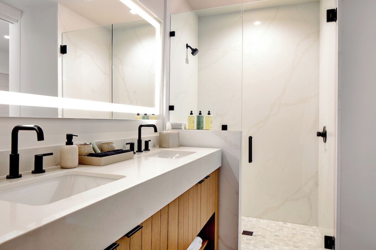 Un baño moderno con lavamanos doble, un espejo grande y zona de ducha.