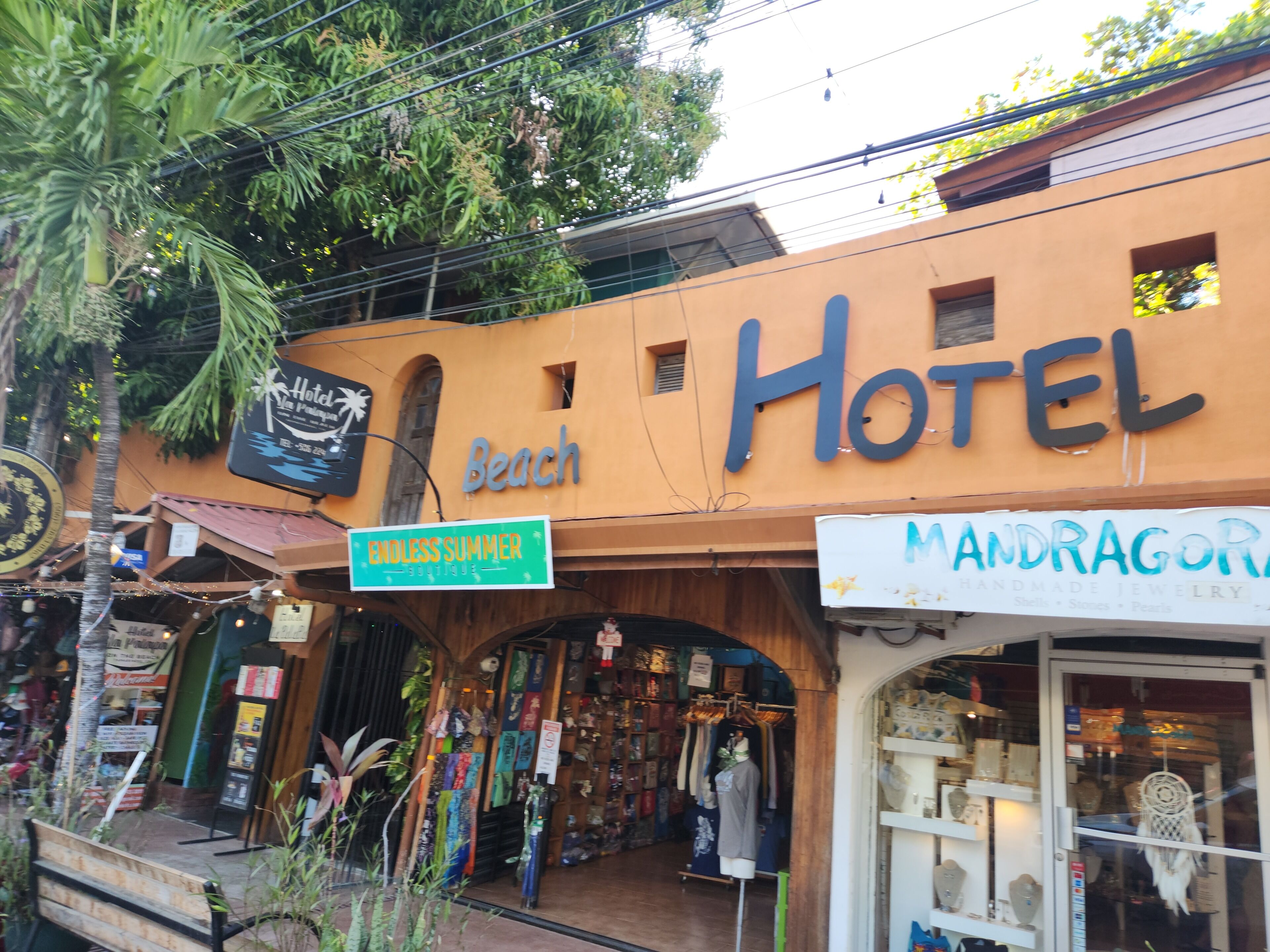 Een hotel met een bord waarop 'Hotel Beach' staat en een ander bord voor 'Endless Summer Boutique'.