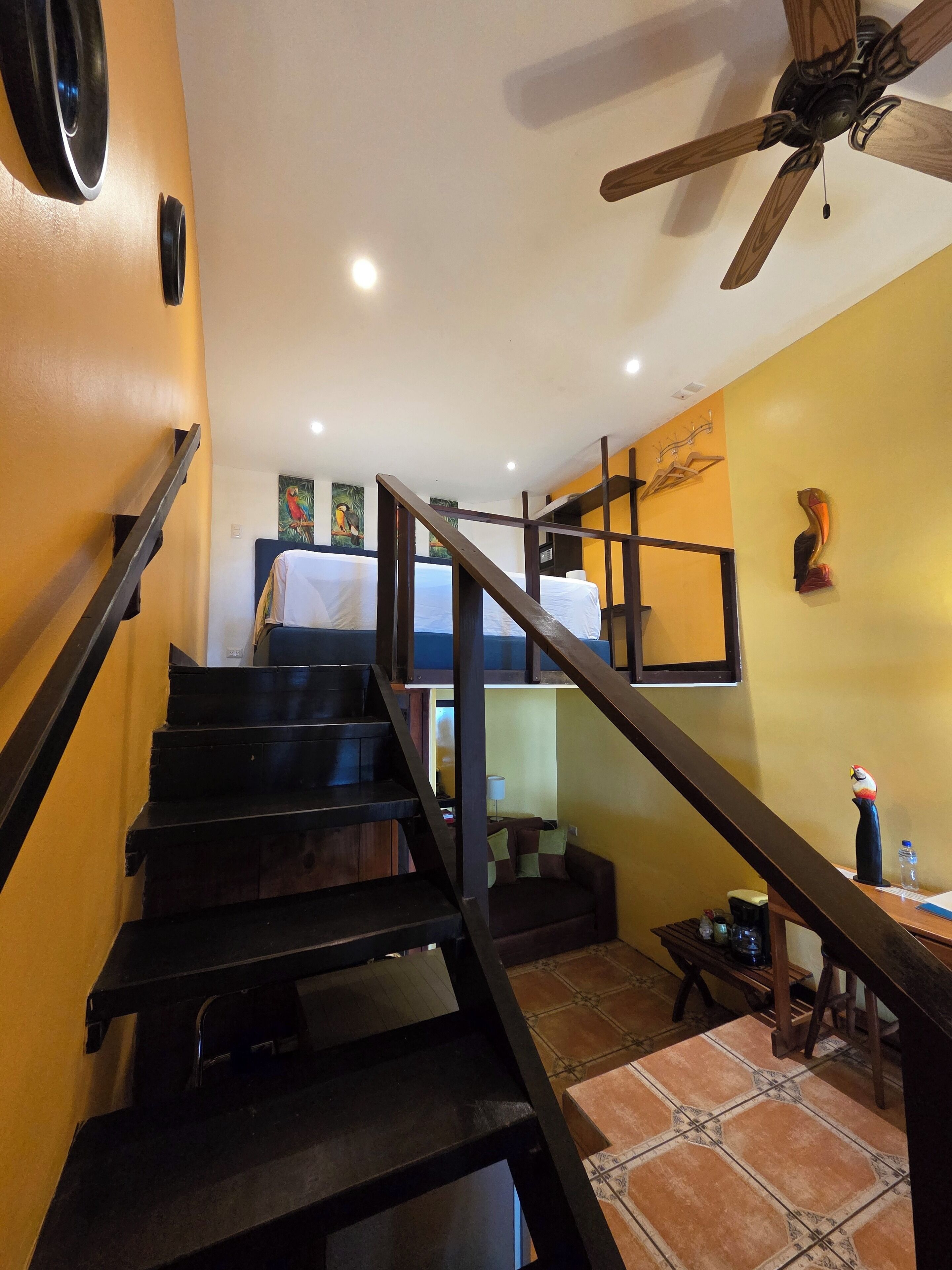 A staircase with a wooden handrail leading to a bed with white bedding.