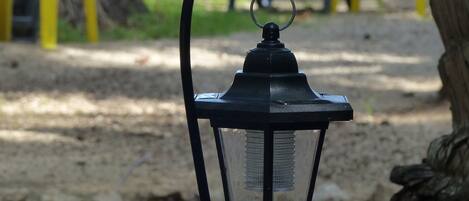 A lantern on a sandy surface with a hammock and yellow railings in the background.