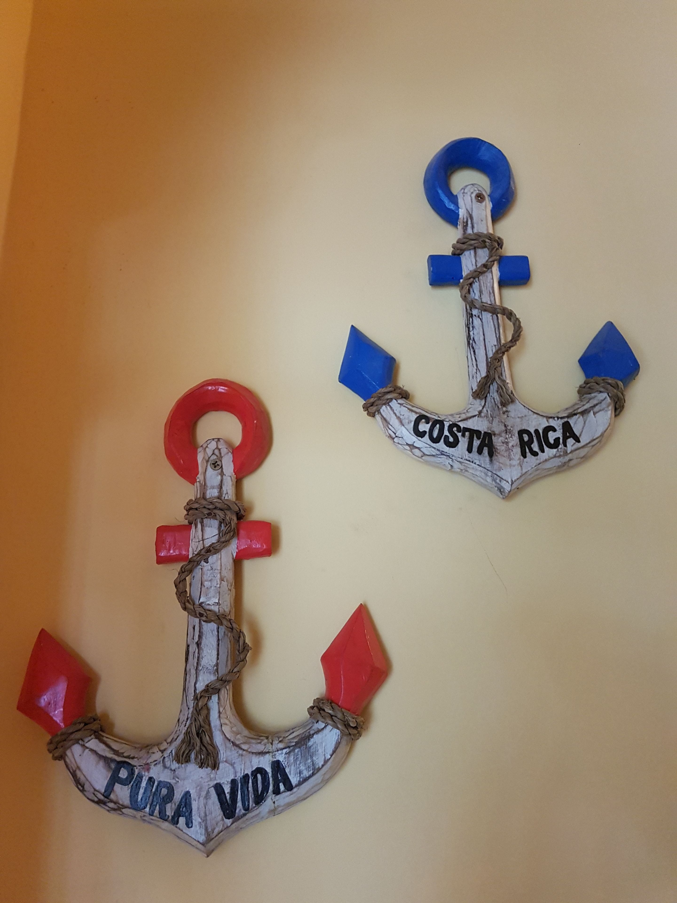 Two decorative anchors with inscriptions on a plain wall.