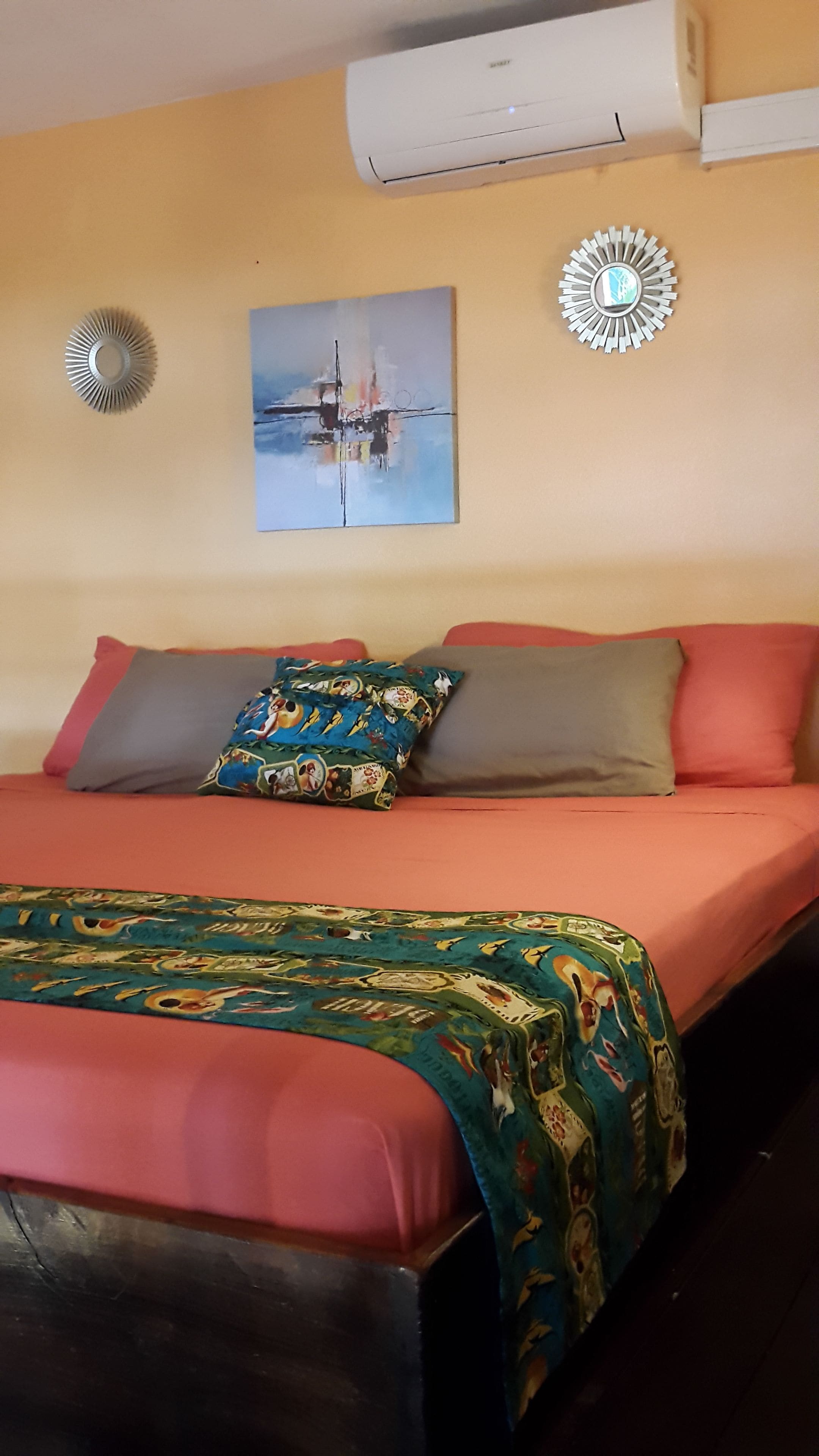 Un dormitori amb un llit, un quadre, aire condicionat i un mirall decoratiu.