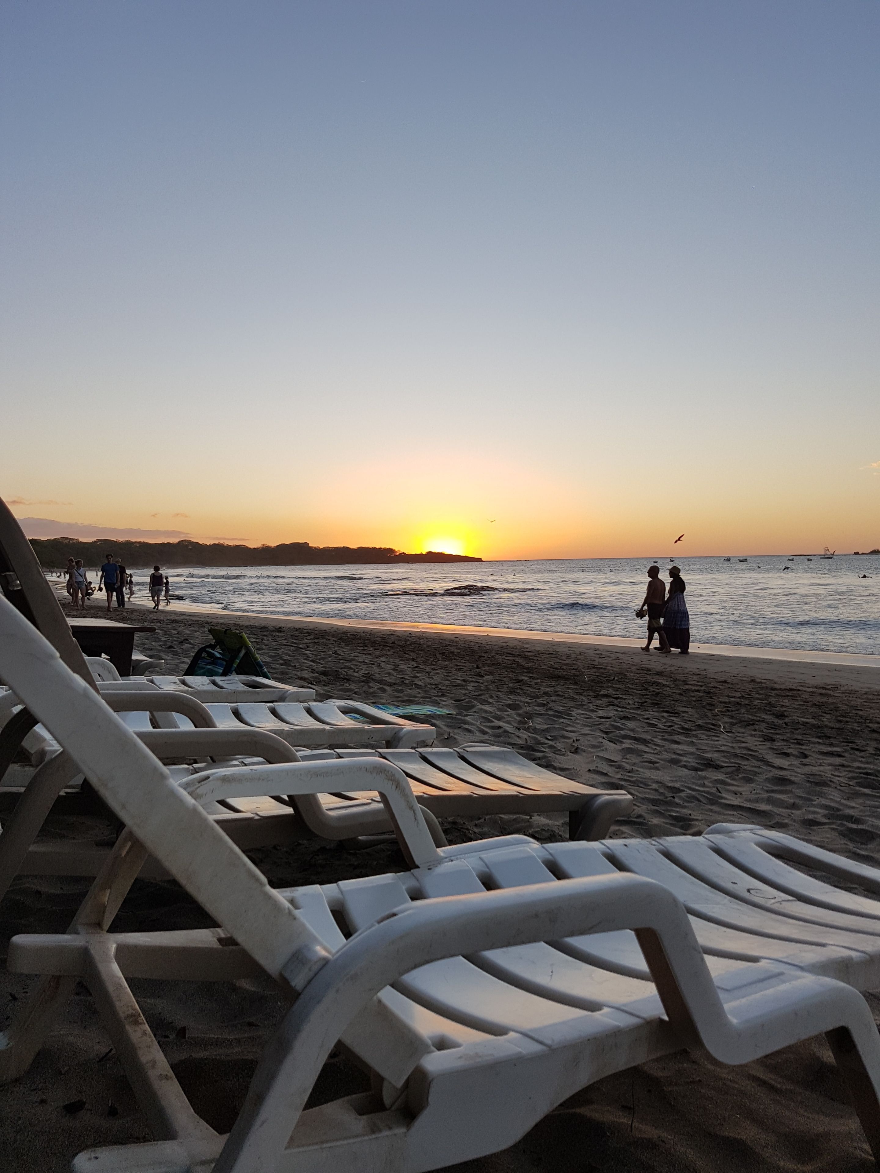 Une plage avec des transats et un coucher de soleil.