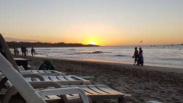 Une plage avec des transats et un coucher de soleil.