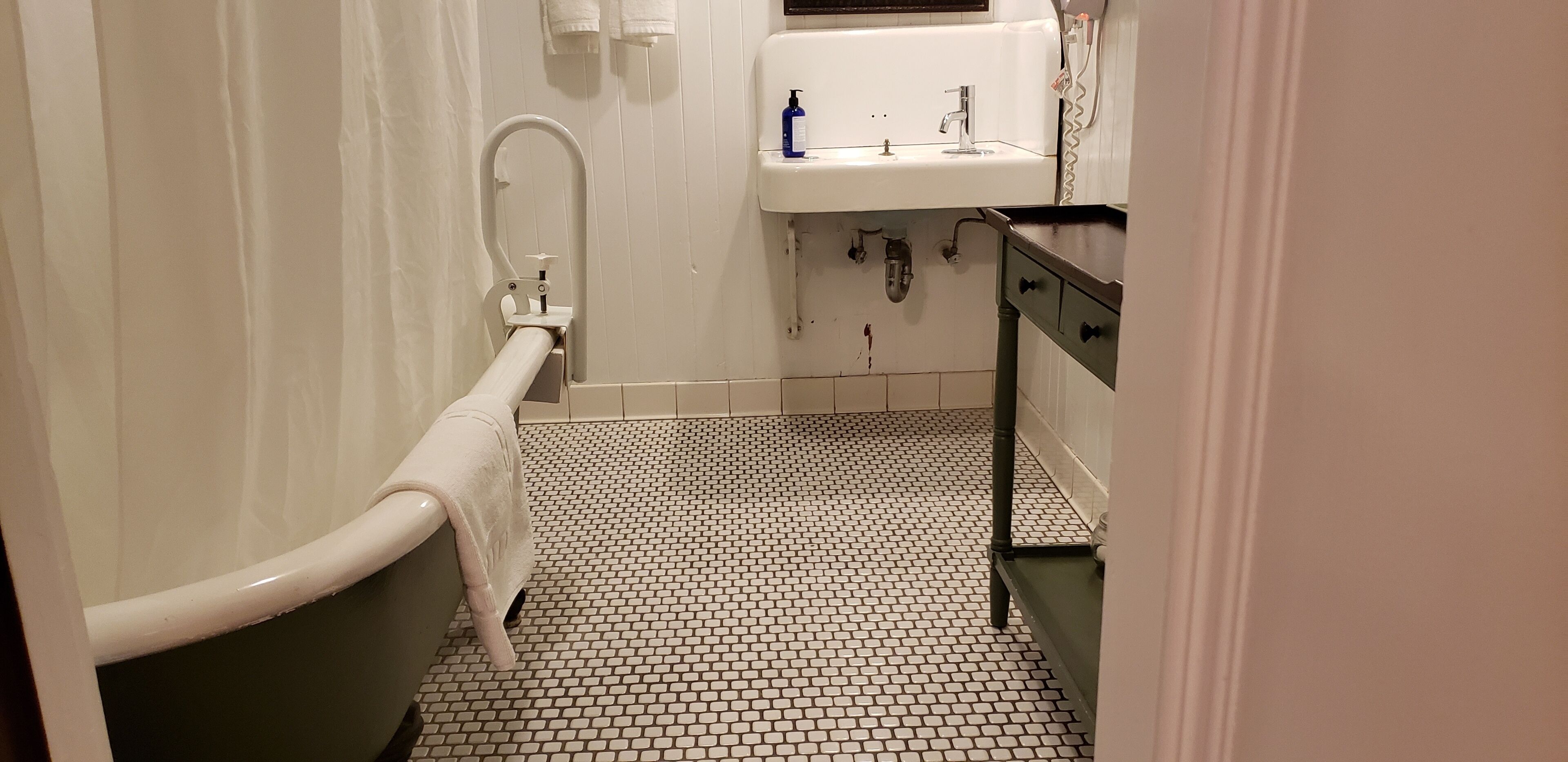 Ein Badezimmer mit einer weißen Badewanne, einem weißen Waschbecken und einem gefliesten Boden.