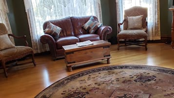 A living room with a brown leather sofa, two armchairs, a wooden coffee table, and a patterned rug.