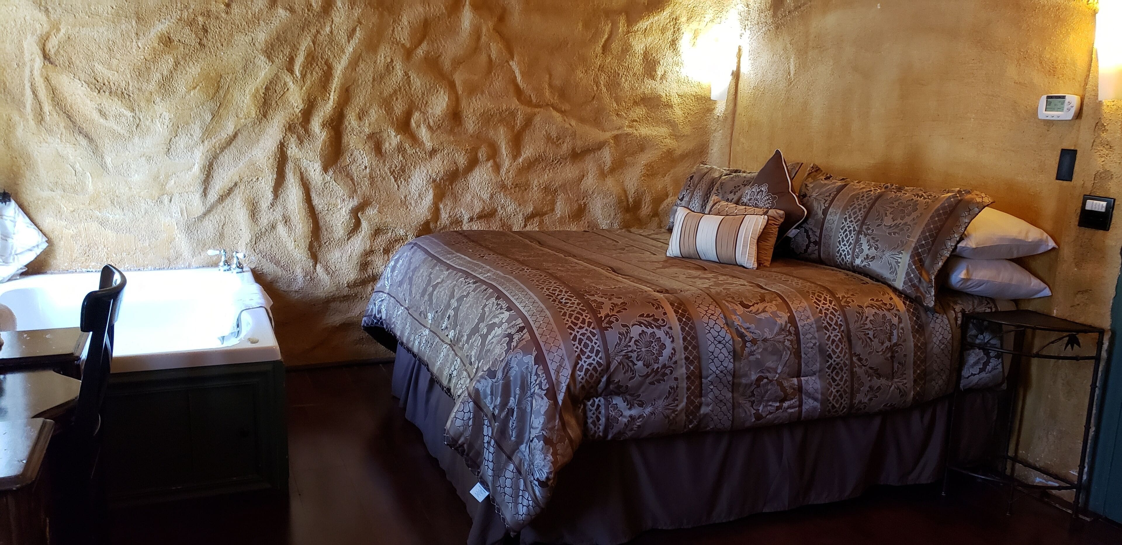 A bedroom with a large bed, a nightstand, a chair, and a bathtub.