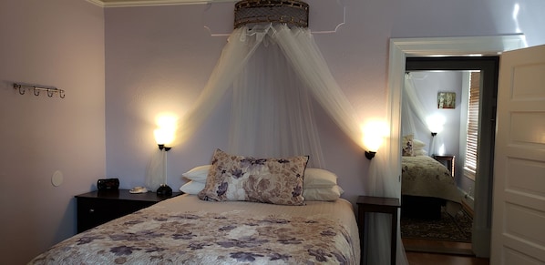 A bedroom with a bed, a nightstand, a wall-mounted lamp, and a canopy bed. - Cabernet House, An Old World Inn (Napa)