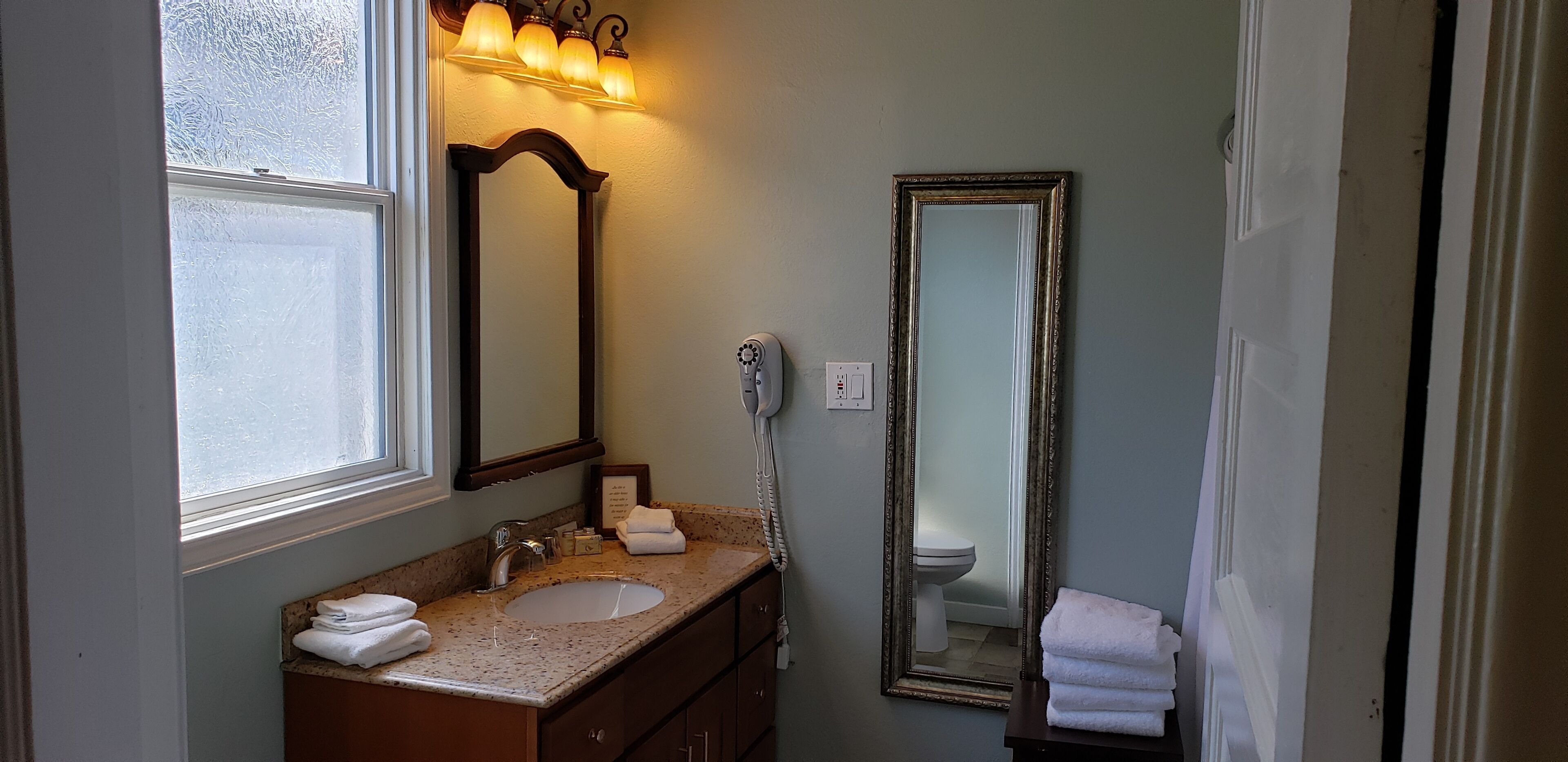 A bathroom with a sink, vanity, and two mirrors.