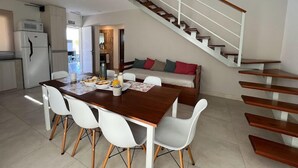 Una cocina moderna con comedor, una escalera y una sala de estar con sofá.