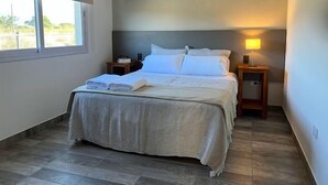 Un dormitorio con cama, mesitas de noche, lámpara y ventana.
