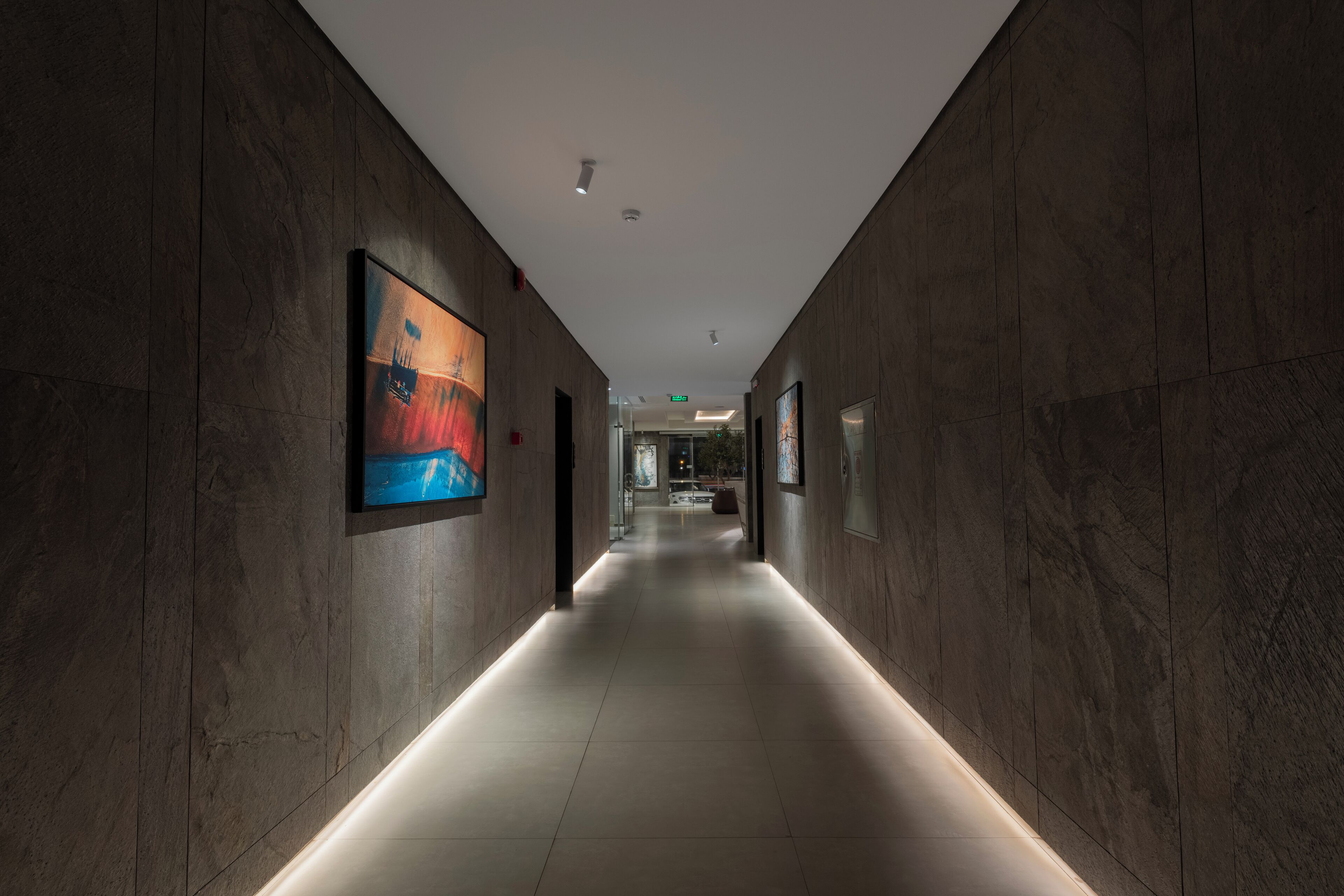 A modern hallway with dark wooden walls, recessed lighting, and a tiled floor.