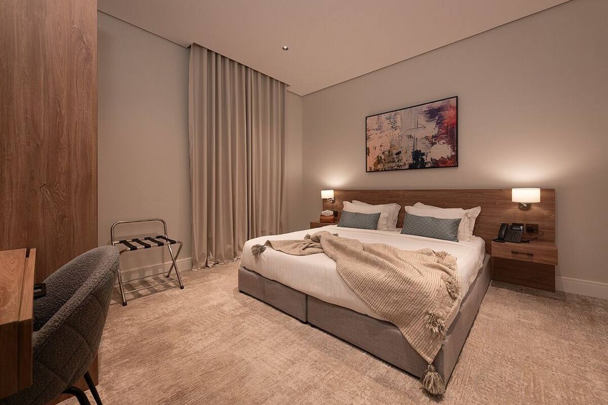 A modern hotel room with a large bed, bedside tables, a desk, and a chair.