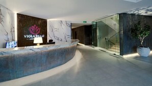A modern reception area with a marble counter, a logo, and a potted plant. - Viola Gardens Residence ( economic serviced apartments) (Riyadh)