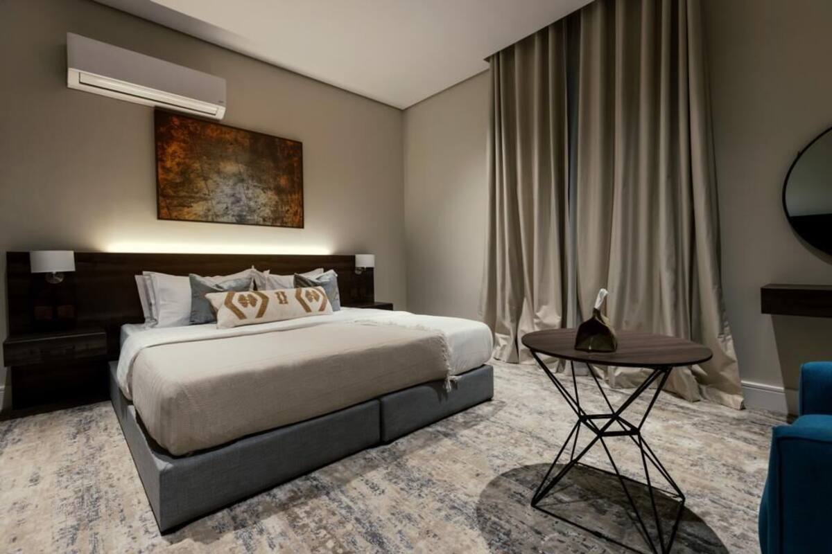 A modern hotel room with a large bed, a small round table, and a painting on the wall.
